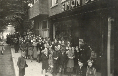 602782 Gezicht op de rij wachtenden voor de winkel van Simon de Wit (Burg. Reigerstraat 57) te Utrecht waar zojuist een ...